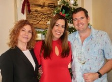 Representatives of Grassini and Storyteller Children's Center posing in front of holiday decorations at annual "Grassini Gives Back" Charity Event